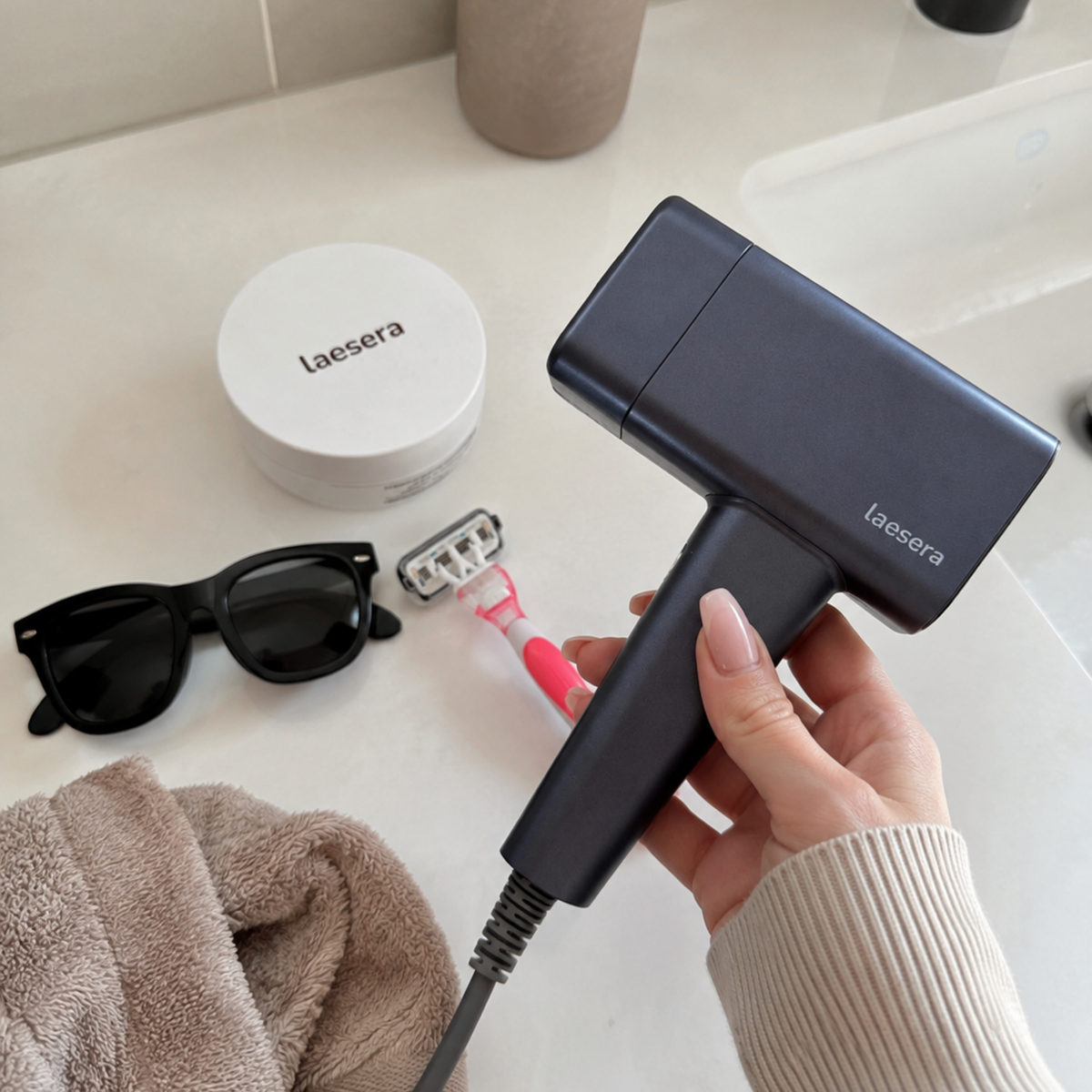 Laesera IPL hair removal device in hand during a bathroom care routine